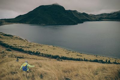 Person walking on mountain towards sea