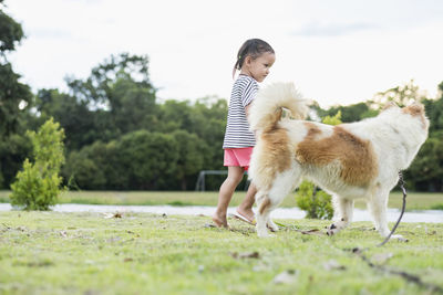 Side view of woman with dogs on field