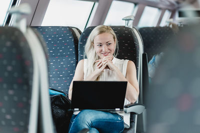 Young woman using mobile phone while sitting in bus