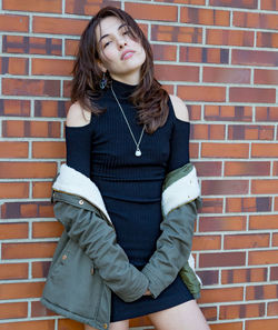 Young woman standing against brick wall