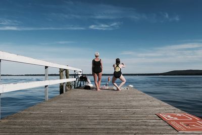 Women standing on pier over sea against sky