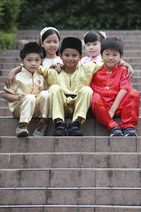Portrait of cute friends in traditional clothing sitting on steps
