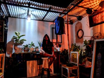 Woman sitting on table in illuminated room