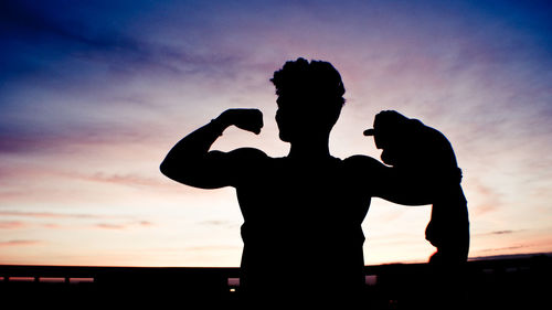 Silhouette couple standing against sky during sunset