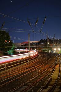 Light trails on railroad tracks against sky at night