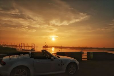 Car on sea against sky during sunset