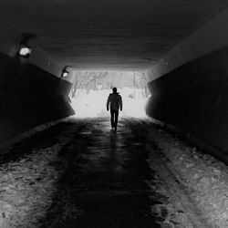 Rear view of silhouette man walking in tunnel