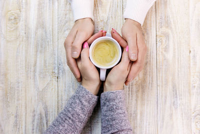 High angle view of woman holding coffee on table