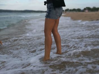 Low section of woman standing on beach