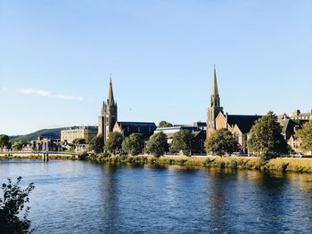 Buildings by river against clear sky