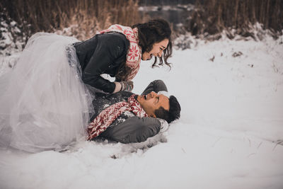 Side view of woman sitting on snow covered field