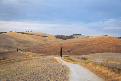 View of a country road and fields after harvest in the hills of tuscany in italy