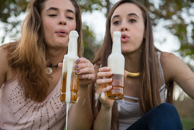 Young female friends holding beer bottles