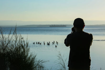 Rear view of man looking at sea against sky