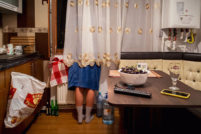 Low section of woman standing on table at home