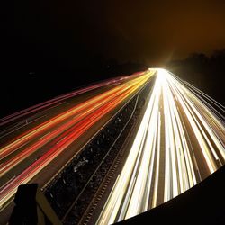 Light trails on road against sky at night