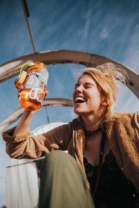 Cheerful young drinking water against sky