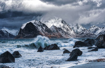 Scenic view of sea and snowcapped mountains against sky