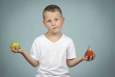 Portrait of boy holding apple against clear sky