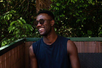 Portrait of young man wearing sunglasses standing against trees