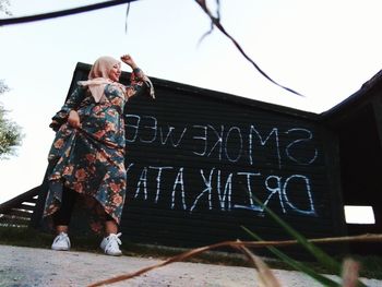 Woman standing by text against sky