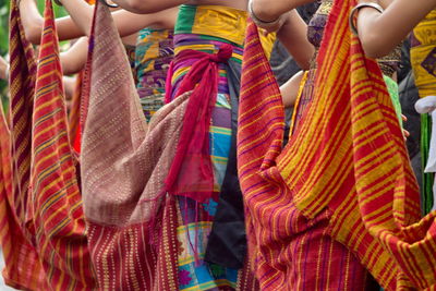 Low section of woman dancing on street with traditional textiles from bali, indonesia.