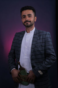 Portrait of young man standing against wall