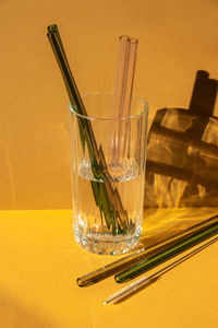 Reusable glass straws in glass with water on beige neutral background eco-friendly drinking straw