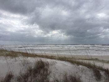 Scenic view of beach against cloudy sky