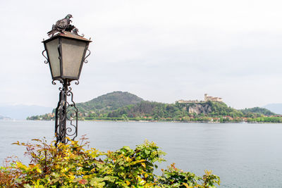 Street light by river against sky