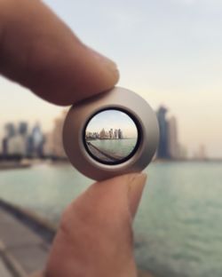 View of river and city seen through lens held by woman