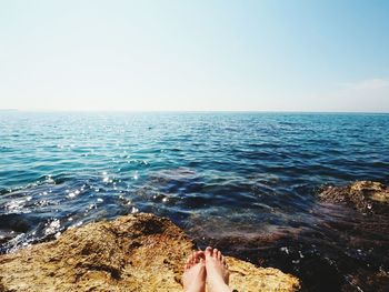 Low section of woman in sea against clear sky