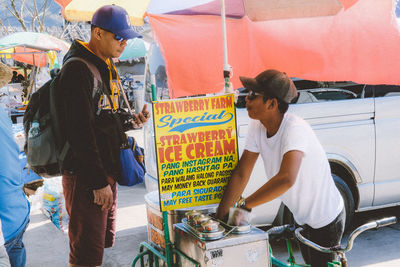 Rear view of people standing at market stall