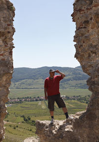 Full length of man standing on rock against sky