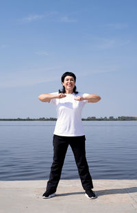 Portrait of smiling man standing in water against sky