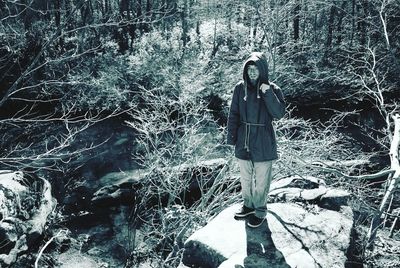 Full length portrait of young woman standing in forest