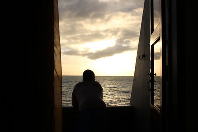 Silhouette people in front of sea at sunset