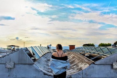 Rear view of woman standing on terrace against cloudy sky