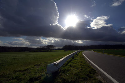 Road amidst field against sky