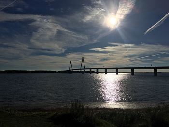 Bridge over river against cloudy sky during sunset