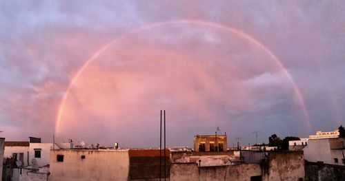 Rainbow over buildings in city against sky