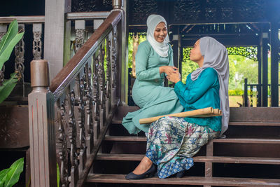 Woman sitting on railing by staircase