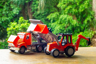 Red toy car on road against trees in city