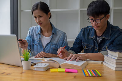 Young woman using mobile phone while sitting on table