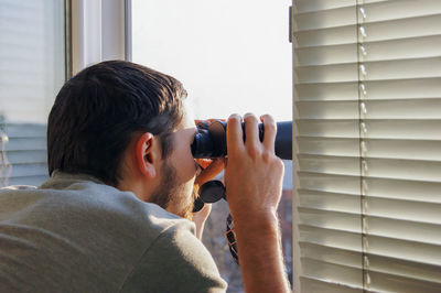 Side view of man photographing through window