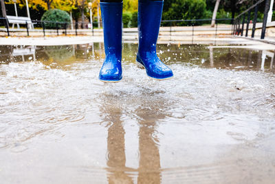 Low section of person jumping in puddle