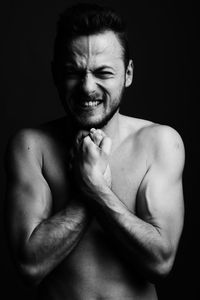 Portrait of young man smiling against black background