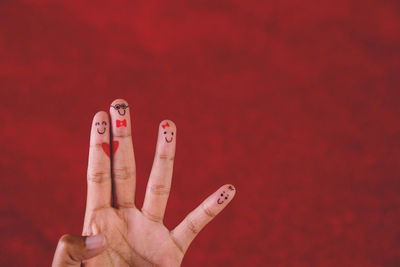 Cropped hand with anthropomorphic smiley face against red background