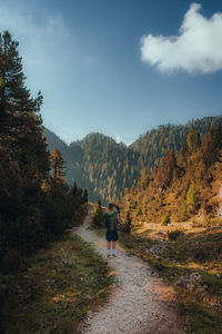 Rear view of man walking hiking on mountain against sky