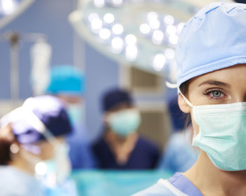 Portrait of female doctor with coworkers in background at operating room